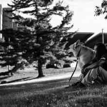 Army veteran Aquil Thomas with his dog on the grass outside of a VA medical center. Photographed by Steve Gibson