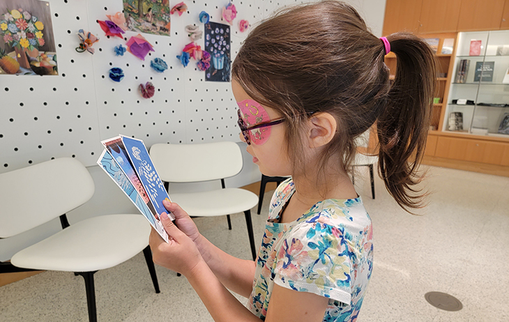 A young girl with dark brown hair looks at set of brightly colored cards.