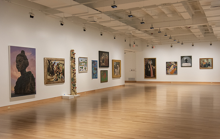 Art displayed in a large room with a wood floor and white walls
