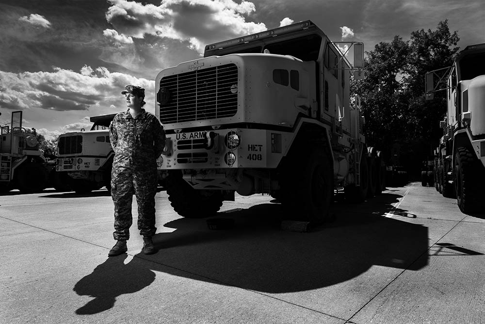 Black and white photograph of Sgt. Tara Arteaga standing in uniform in front of a truck