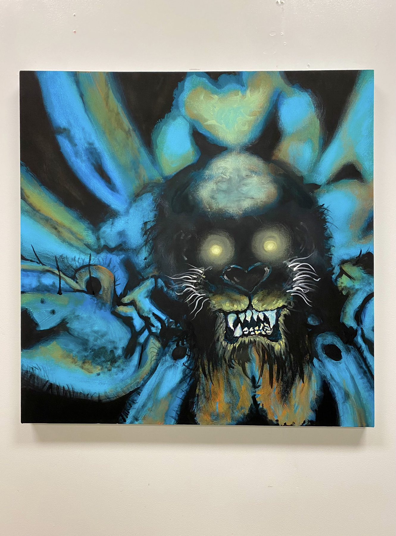 The head of a snarling, wolf-like figure with glowing yellow eyes emerges from a blurry black and blue background with yellow-orange highlights 