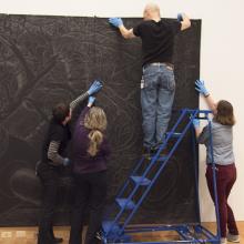 Head of Collections Sofia Galarza Liu, artist Sandy Winters, Exhibition Designer Richard Klocke, and assistant collections manager Sarah Schroeder affix a portion of <i>Long Night's Journey into Day</i> in the Perkins Central Court