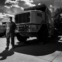 Sergeant Tara Fajardo Arteaga, who has served in the Army National Guard since 2008, stands in uniform in front of a truck. Photographed by Steve Gibson